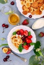 Porridge of tiny pancakes with berries, cream and honey