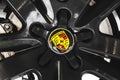 Porsche brand logo on a black car wheel background, emblem, symbol close-up