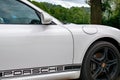 Porsche Cayman in white and black. Sporty German car with a green countryside background