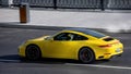Porsche 992 is eighth generation of the Porsche 911 sports car. Yellow premium car in motion on the street