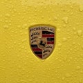 Porsche logo closeup, yellow sports car, rain drops