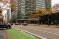 The Porsche store downtown with yellow autumn trees, people walking, office buildings and cars driving on the street