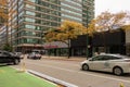 The Porsche store downtown with yellow autumn trees, people walking, office buildings and cars driving on the street