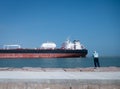 PORT ARANSAS, TX - 26 FEB 2023: Fisherman and tanker ship on water