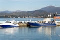 Port on the background of mountains - parked boats, a pleasure boat, a trailer. Fishermen are fishing. Royalty Free Stock Photo