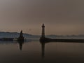 Port basin of Lindau, Lake Constance, Germany with lighthouse and lion sculpture on winter day.