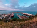 Port bay in Napier New Zealand in sunset on blue water ocean, orange, teal, blue ship cruise cargo containers shipping carry