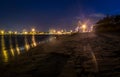 A port and beach at night with lights and star rays Royalty Free Stock Photo