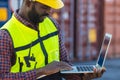 Port cargo staff worker using laptop computer online to manage control loading container in logistics industry