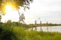 Port cranes with a bucket on the river bank, extraction of river sand, the sun Royalty Free Stock Photo