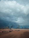 Port cranes under the dark clouds after the thunderstorm. Dramatic stormy sky. Industrial landscape. Idle cranes in front of storm