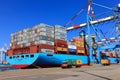 Port dock with container ship and Various brands and colors of shipping containers stacked in a holding platform Royalty Free Stock Photo