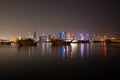 Port of Doha, Qatar at night with its skyline and old traditional dhows ships