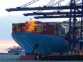 Port of Felixstowe, Suffolk, UK, February 11 2018: Cranes loading containers onto the Ebba Maersk cargo ship at dusk