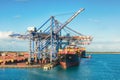 Port of Freeport Bahamas Container shipyard with heavy lifting Cranes and a ship coming in to dock assisted by tug boats Royalty Free Stock Photo