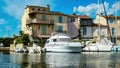 View over water canal on private pier with luxury yachts at resedential building against blue summer sky