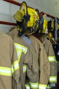 Bright yellow fire fighter helmets and jackets on hangers at a fire station Royalty Free Stock Photo