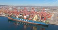 AERIAL: Cranes move shipping containers from docks and onto massive cargo ship
