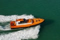 Port pilot on small vessel moving at high speed. Small orange boat shipping on sea water. Pilot boat for guidance into harbor.Equi