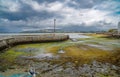 Port of Rianxo at low tide. Green algae and two anchored fishing boats under a gray cloudy sky in the background Royalty Free Stock Photo