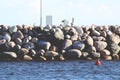 Port shore made of large stones with a red buoy in the water