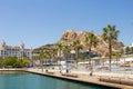 Port side embankment in Alicante, Spain. Sidewalk near marina, palm trees, historical buildings on background