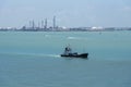 Port of Singapore, fishing boat sailing near cargo terminal.