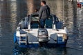 08/30/2020 Port solent, Portsmouth, Hampshire, UK a man driving a small boat in a marina showing the boats engine and the wake of