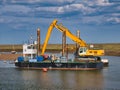 In the Port of Wells, Norfolk, UK, harbour dredger Kari Hege, a specialist 20m by 10m spud-leg pontoon with depth monitoring