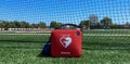 Portable AED defribrillator resuscitation machine on a turf field in front of a black net Royalty Free Stock Photo