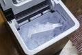 A portable automatic ice maker with the lid open, showing an ice cube tray full of ice with a white scoop Royalty Free Stock Photo