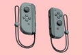 Portable black video game controllers on the rope on pink background