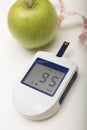 Portable blood glucose meter with a green apple Royalty Free Stock Photo