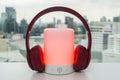 Portable Bluetooth speaker in red color with cute pink wireless headphones for pairing to listen to music