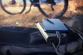 Portable charger charges the smartphone. Power Bank with cable against the background of bicycle