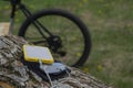 A portable charger charges the smartphone. Power Bank with cable against the background of wood and bicycle Royalty Free Stock Photo