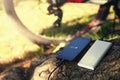 A portable charger charges the smartphone. Power Bank with cable against the background of wood and bicycle Royalty Free Stock Photo