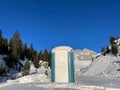 Portable chemical toilet in idyllic snow-covered winter landscape.