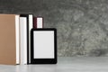 Portable e-book reader and many hardcover books on white textured table, space for text Royalty Free Stock Photo