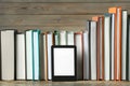 Portable e-book reader and many hardcover books on wooden table Royalty Free Stock Photo