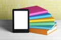 Portable e-book reader and stack of books on white wooden table Royalty Free Stock Photo