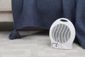 Portable electric fan heater on floor near sofa indoors Royalty Free Stock Photo