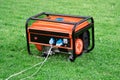 Portable electric generator with electric wires connected on the green grass in summer Royalty Free Stock Photo