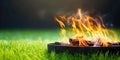 A portable fireplace with bright burning fire woods against grass background.