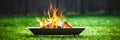 A portable fireplace with bright burning fire woods against grass background.