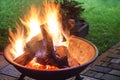 A portable fireplace with bright burning firewood making sparks and smoke at the backyard or garden near house. A place for eveni