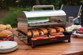 portable grill with hot dogs and buns ready to be cooked on the go