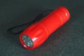 Portable LED flashlight red color isolate on a grey background. Close-up