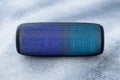 A portable music column on gray grunge concrete background. Musical wireless speaker with blue glow. Sound system