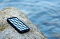 Portable powered solar usb located on a stone on the beach. Alternative energy. Eco Royalty Free Stock Photo